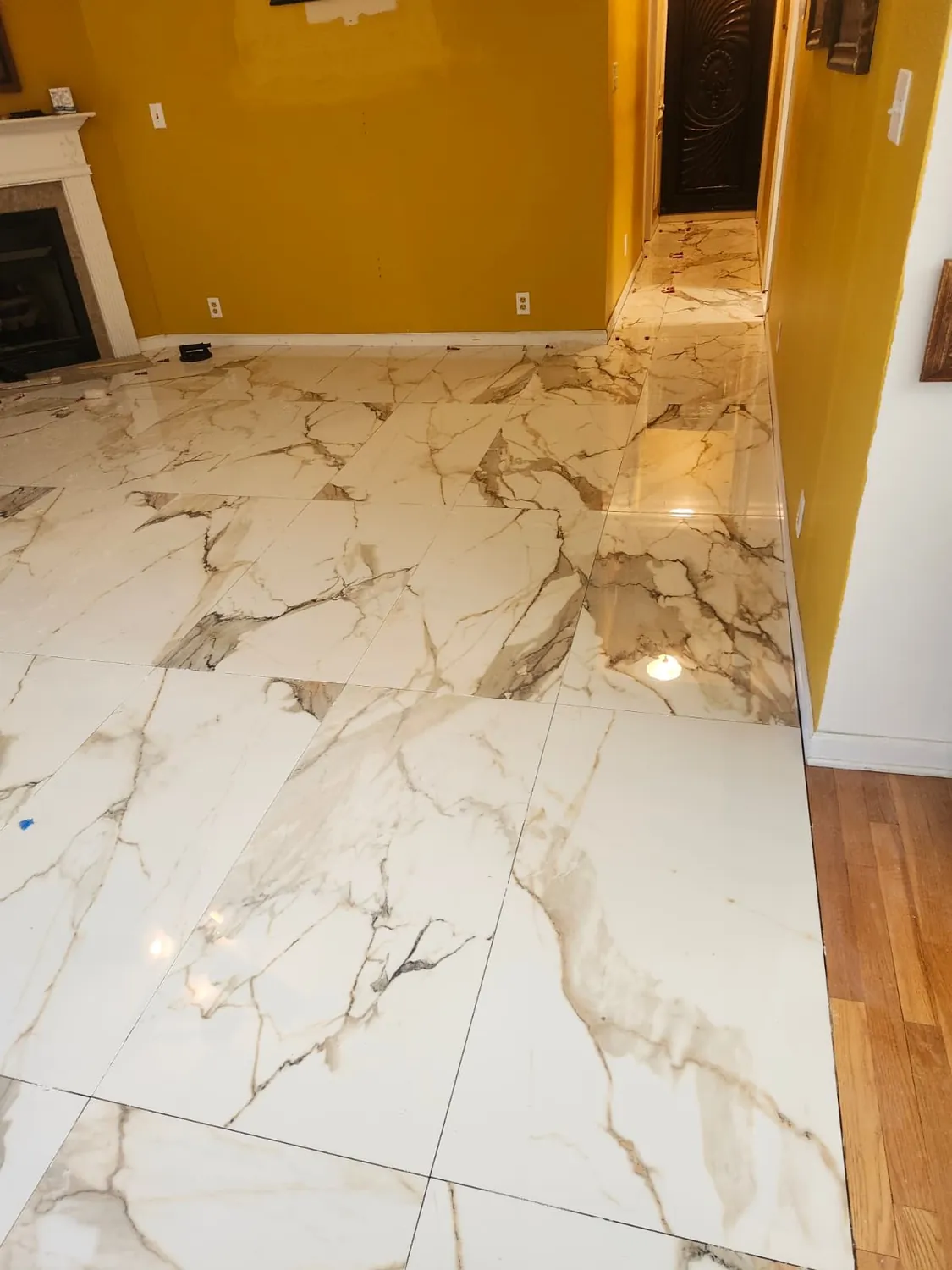 Large-format marble-look tile floor set against existing hardwood